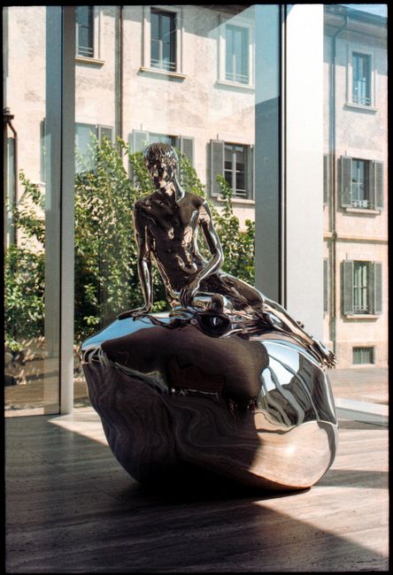 Modern chrome sculpture in a Milan gallery setting, reflecting natural light.