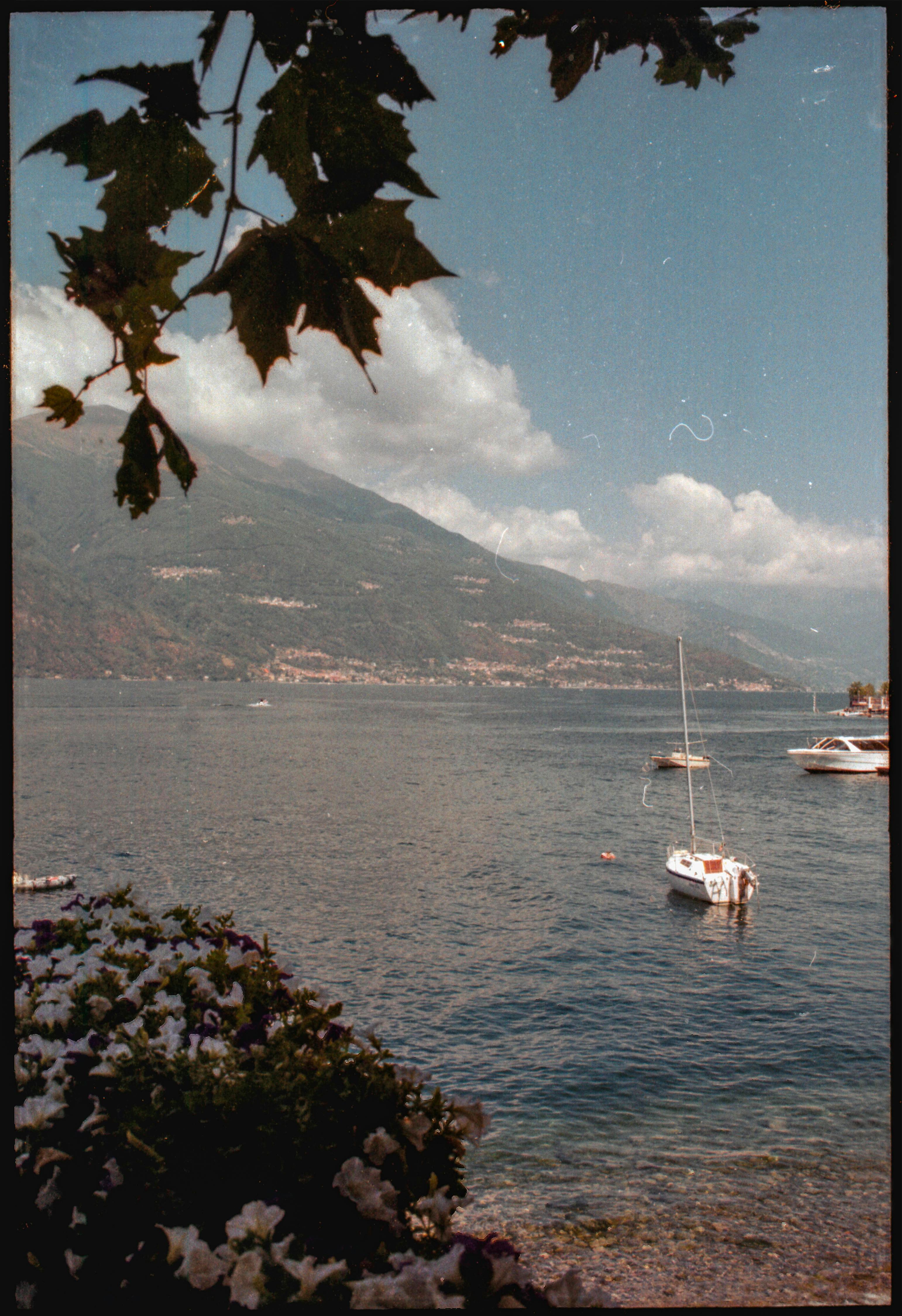 Tranquil view of boats on Lake Como with mountainous backdrop under a clear sky.