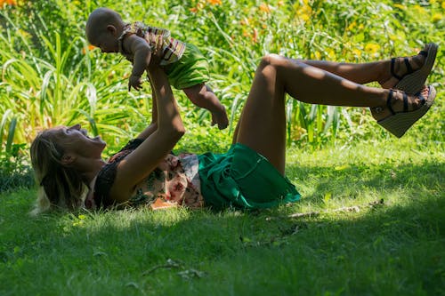 Woman Lying on Grass Playing with a Baby