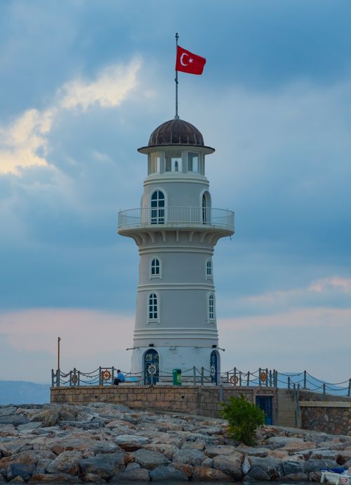 Free Majestic Alanya Lighthouse beneath a cloudy sky, flying the Turkish flag, in Antalya, Türkiye. Stock Photo
