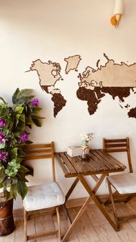 Charming cafe setup with wooden furniture and world map art on the wall.