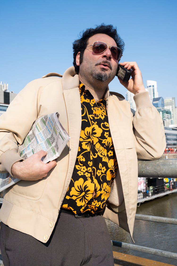 Portrait Of A Man In A Yellow Patterned Shirt Standing With Newspaper On A Footbridge