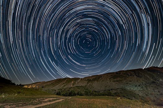 Captivating star trails forming circles above a serene mountain scene, captured with long exposure.
