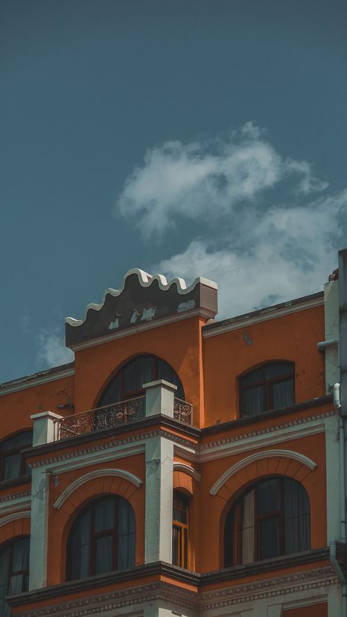Free Low angle view of an orange building with decorative facade and blue sky background, ideal for architecture themes. Stock Photo