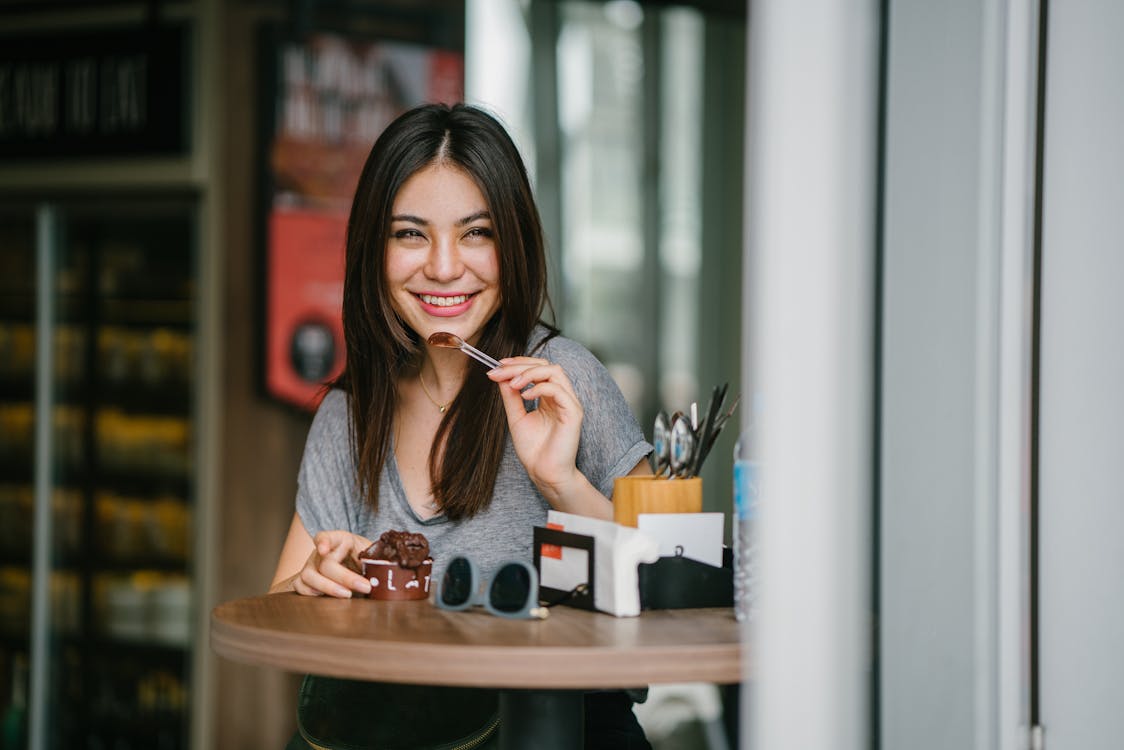 Free Woman Sitting at Table Holding Ice Cream Stock Photo