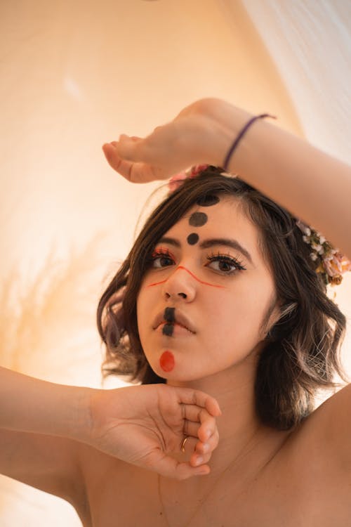 portrait of a young millennial woman with alternative makeup and face paint wearing a flower crown with warm lighting and a dreamy effect caused by intentional blurring