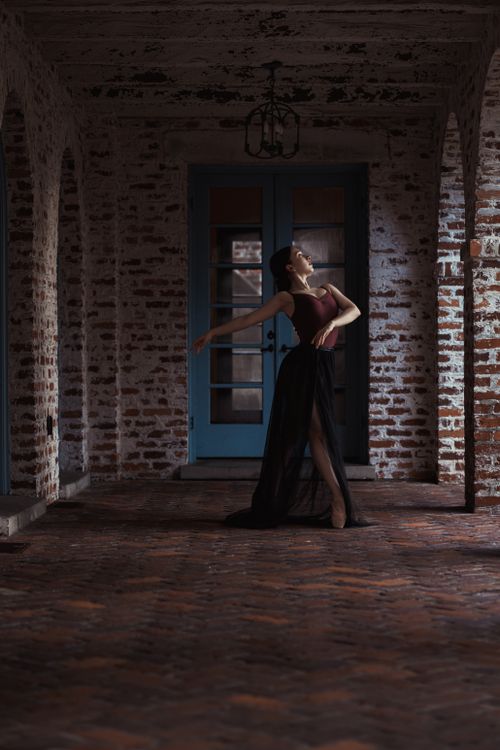 Free Ballerina gracefully dancing in a historic brick corridor, capturing elegance and motion in a serene setting. Stock Photo