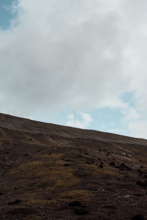 Free Wide view of a calm mountain landscape under thick white clouds and a vast sky. Stock Photo
