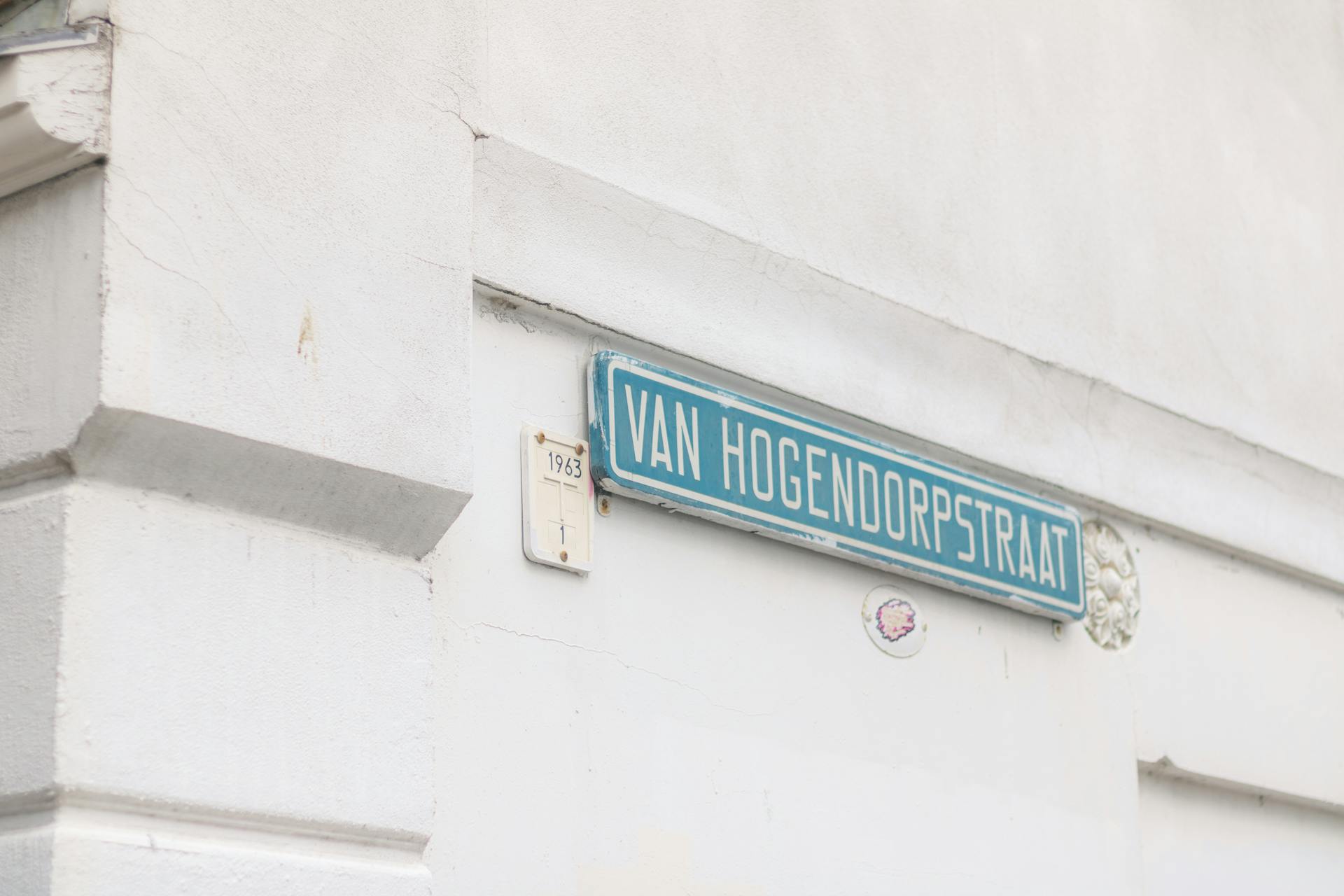 Close-up of Van Hogendorpstraat street sign on a textured white wall, providing urban aesthetic.