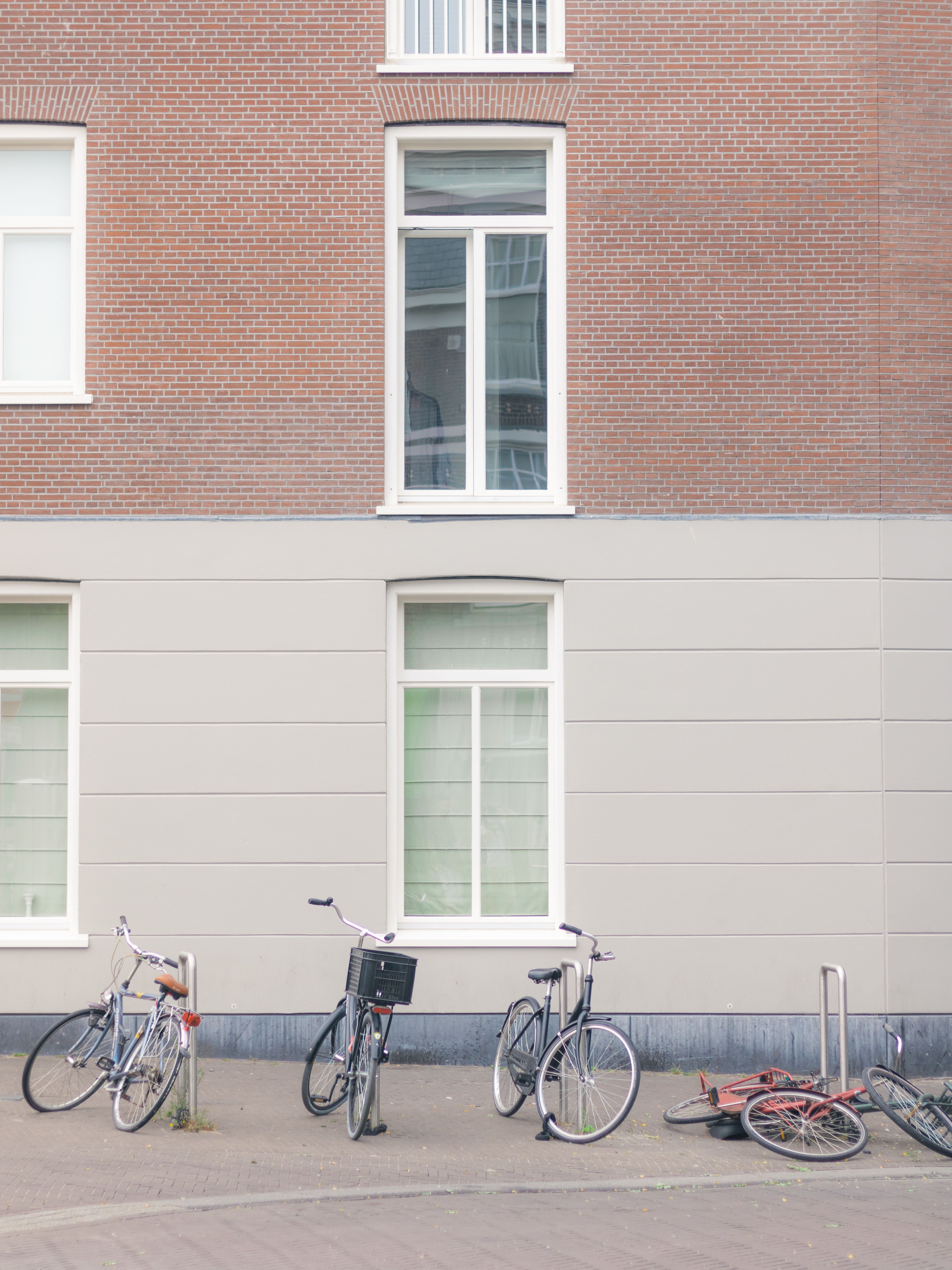 A serene urban street with parked bicycles against a brick building wall.