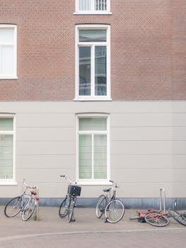 A serene urban street with parked bicycles against a brick building wall.