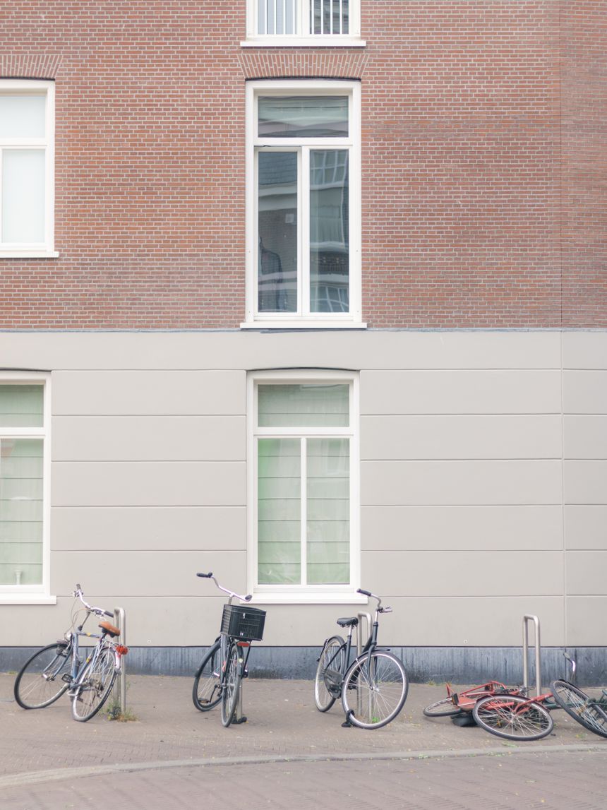 Developed frame: bicycles parked against a brick and render facade on a quiet street. Photo by Marton Novak on Pexels