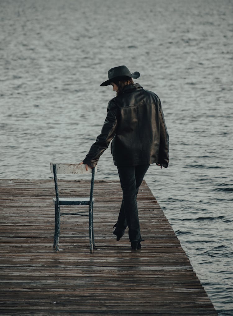 Back View Of A Woman In A Black Leather Jacket Wearing A Hat