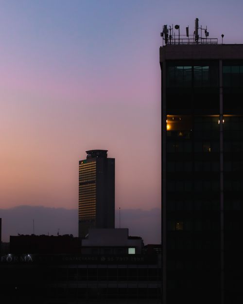 Free A serene view of Mexico City's skyline at dusk with prominent skyscrapers silhouetted against a colorful sky. Stock Photo