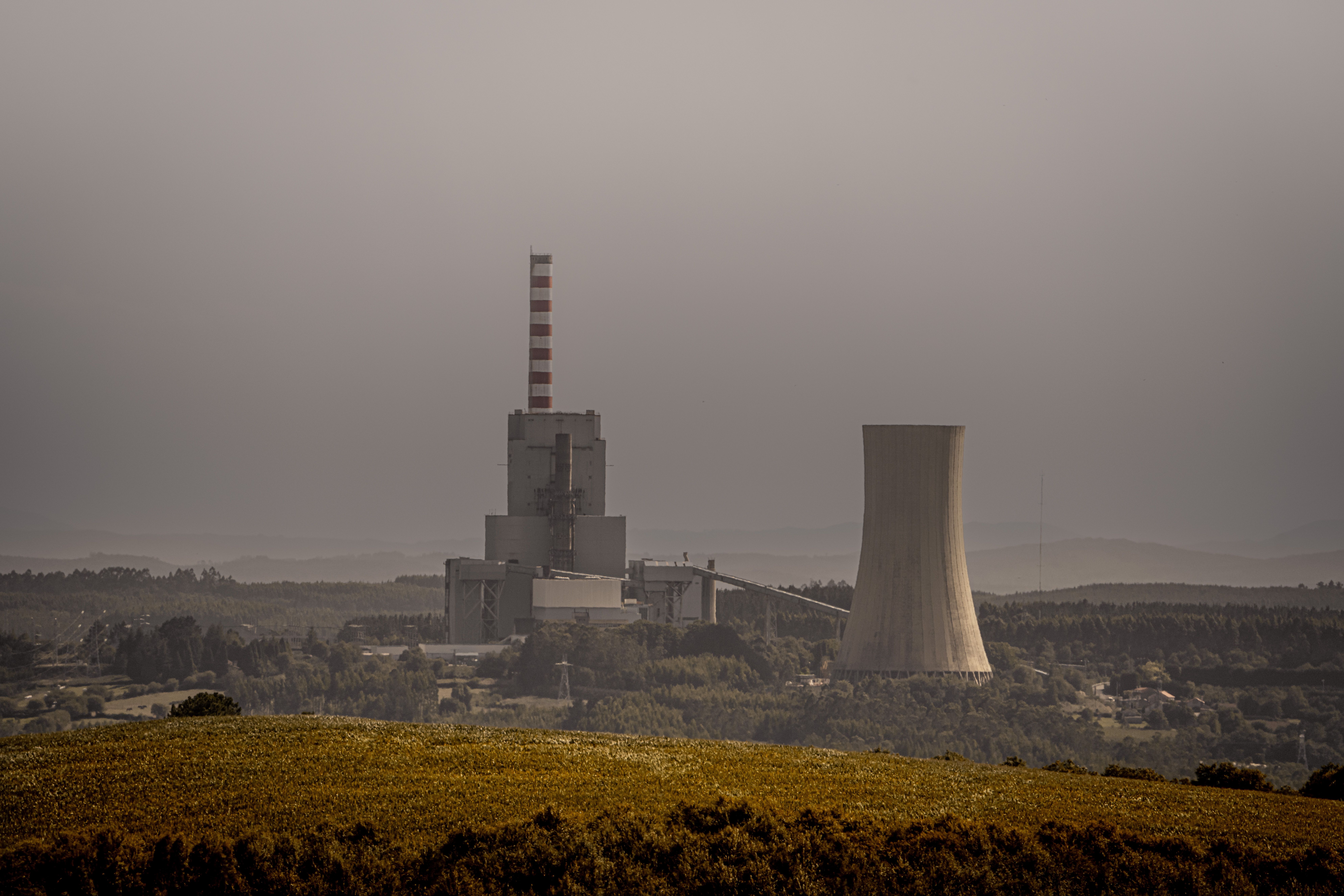 Coal-fired power station with cooling towers and smokestacks under an overcast sky