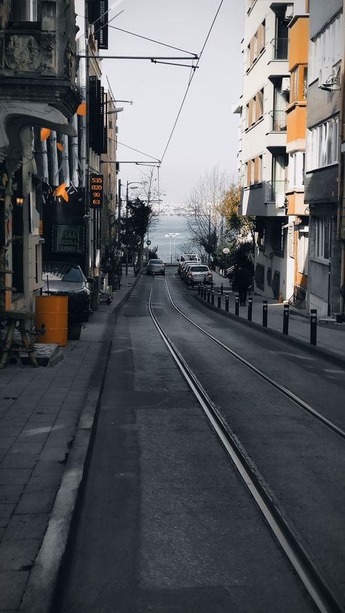 Free A vibrant street in Istanbul featuring tram tracks and historic buildings, leading towards the sea. Stock Photo