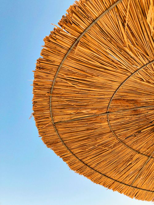 Free Close-up of a straw parasol against a clear blue sky, showcasing texture and pattern. Stock Photo