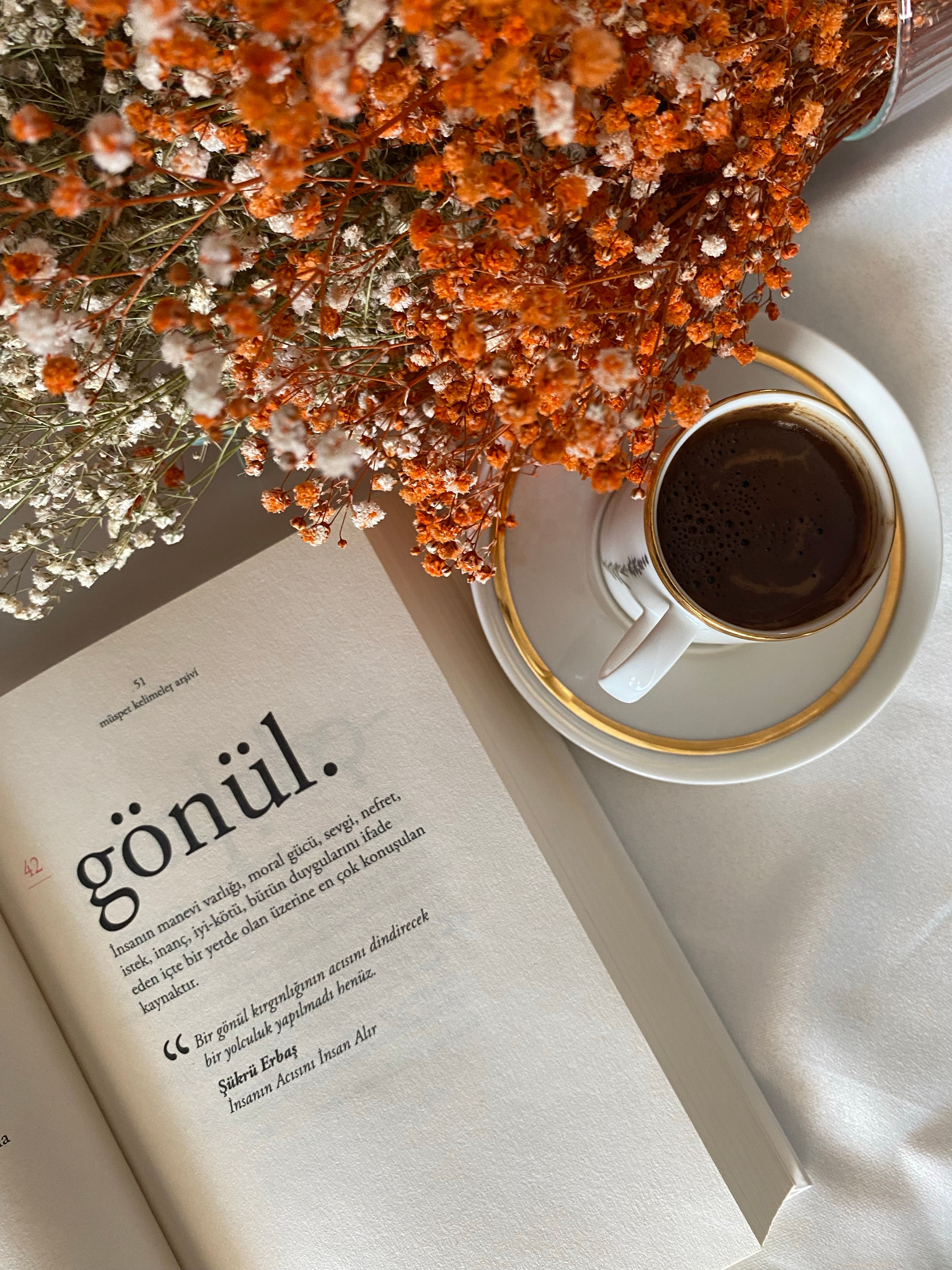 Beautiful still life featuring a book, coffee cup, and dried flowers in a serene composition.