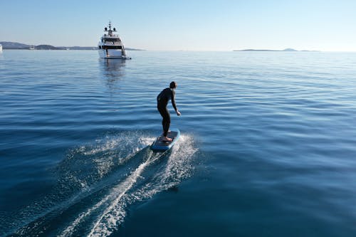 A Man in Black Wetsuit Surfing on Sea