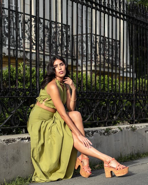 A Woman in Green Sleeveless Dress Sitting on Concrete Bench