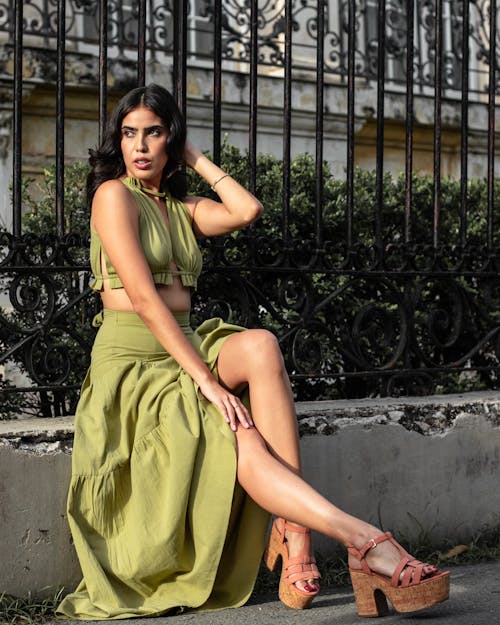 A Woman in Green Dress Sitting on the Sidewalk