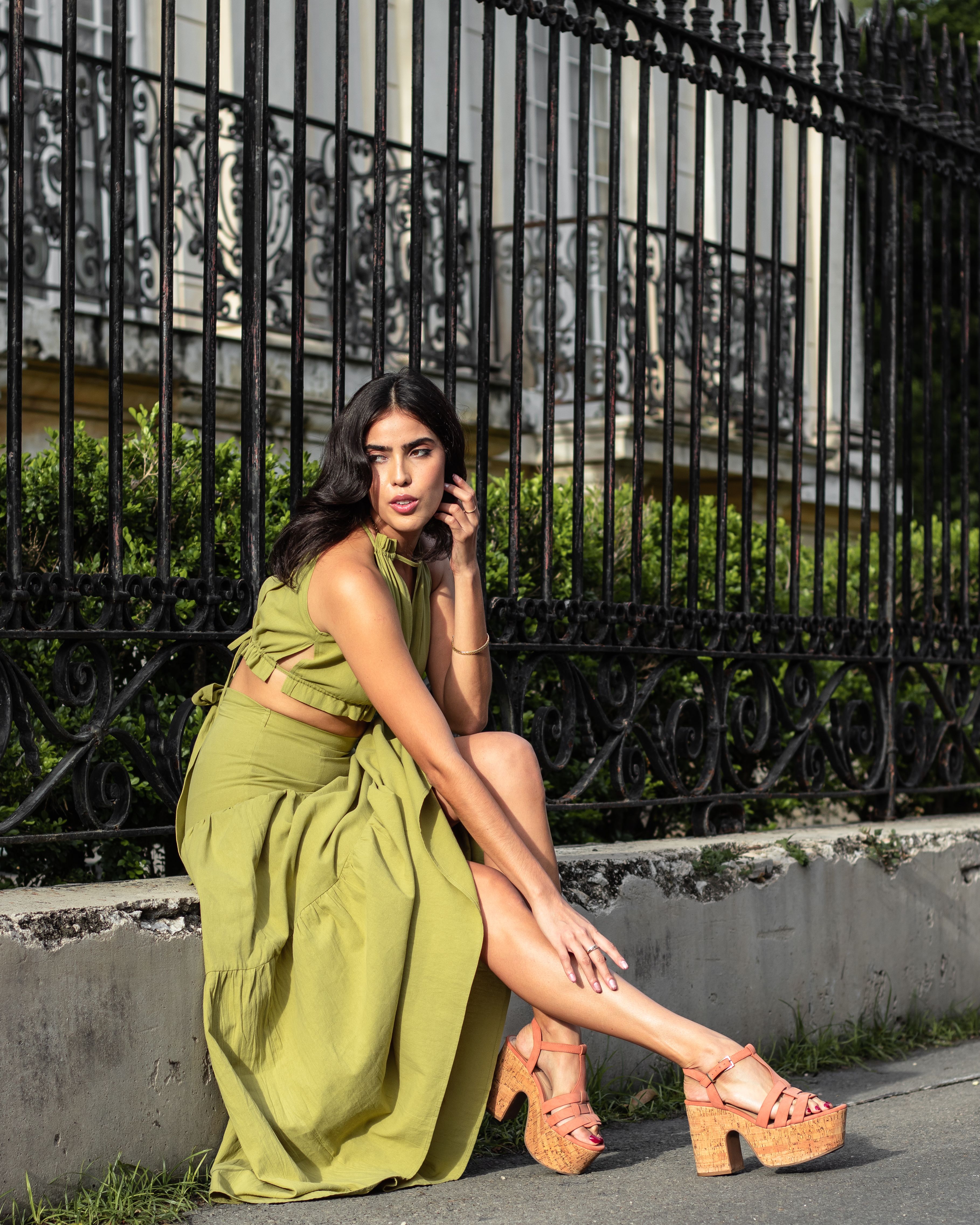 A Woman in Green Dress Sitting Beside the Metal Railings · Free Stock Photo