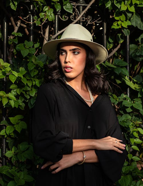 A Woman in Black Dress Standing Beside Green Plants