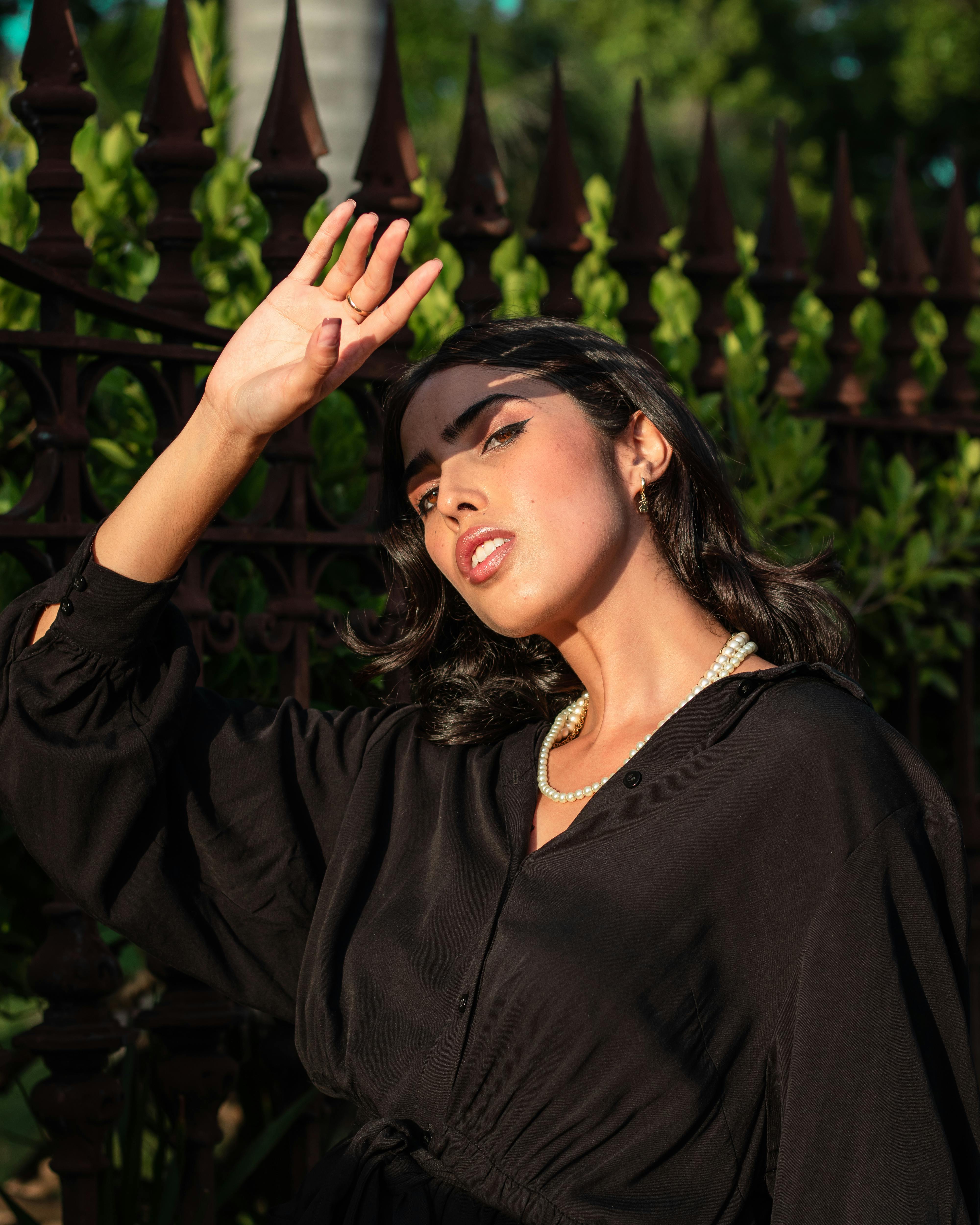 a woman in black long sleeve dress wearing a pearl necklace