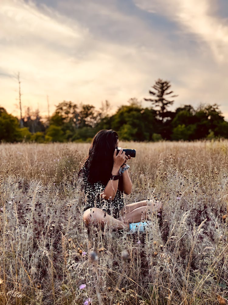 Woman Sitting In Grass Taking Photo