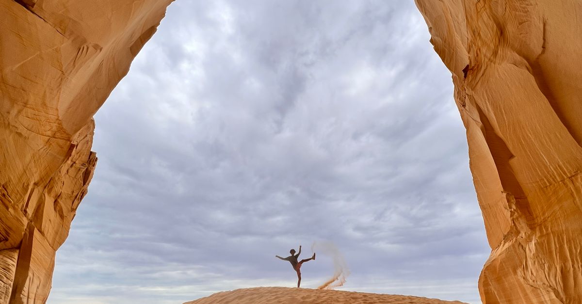Person Looking Under Rocks Person Standing on Brown Sand Under Rock Formation · Free Stock Photo