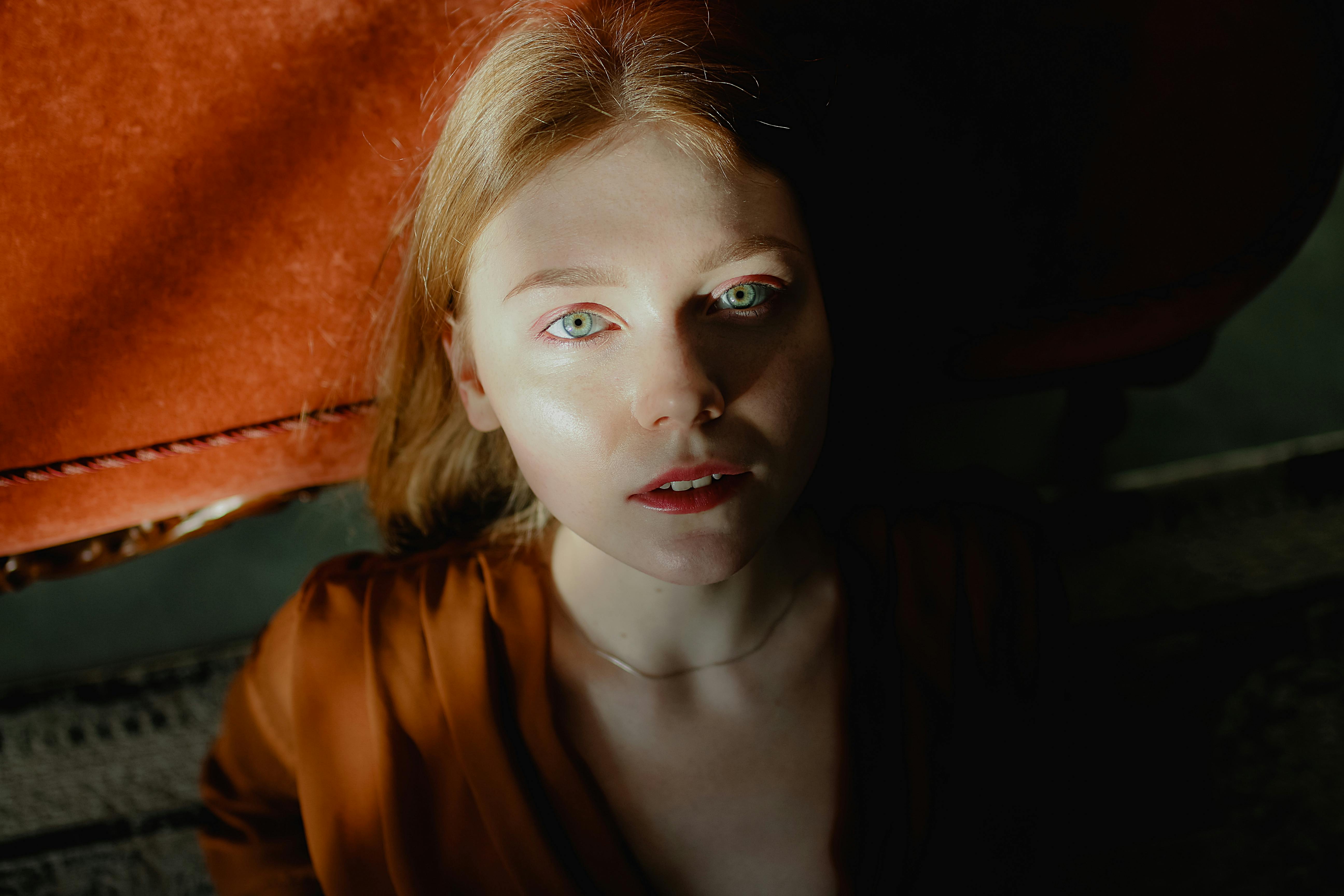 这是一幅迷人的肖像，描绘了一位拥有绿色眼睛的年轻女子，沐浴在戏剧性的室内灯光中