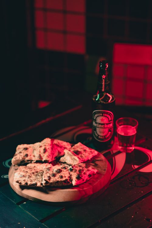 Free Warm ambiance with gourmet pizza and beer on a wooden tray. Perfect for food lovers. Stock Photo