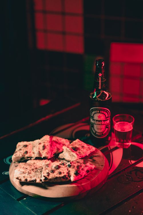 Free Warm and inviting image of a beer bottle, a glass, and bread slices on a wooden tray, perfect for bar ambiance. Stock Photo