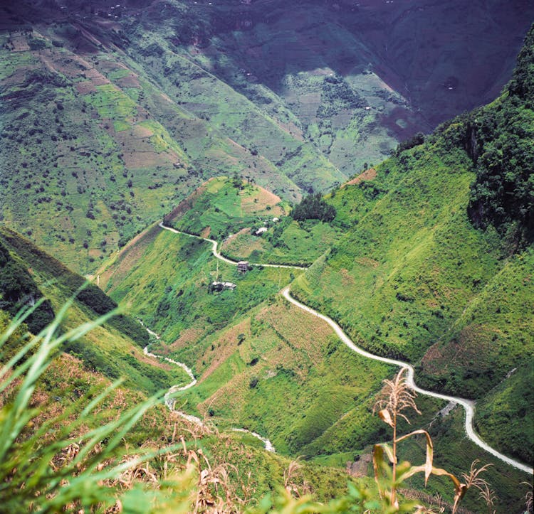 Winding Road Stretching Through A Green Mountain Valley