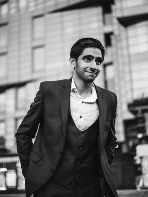Free Black and white photo of an adult man in a suit smiling with hands in pockets. Stock Photo