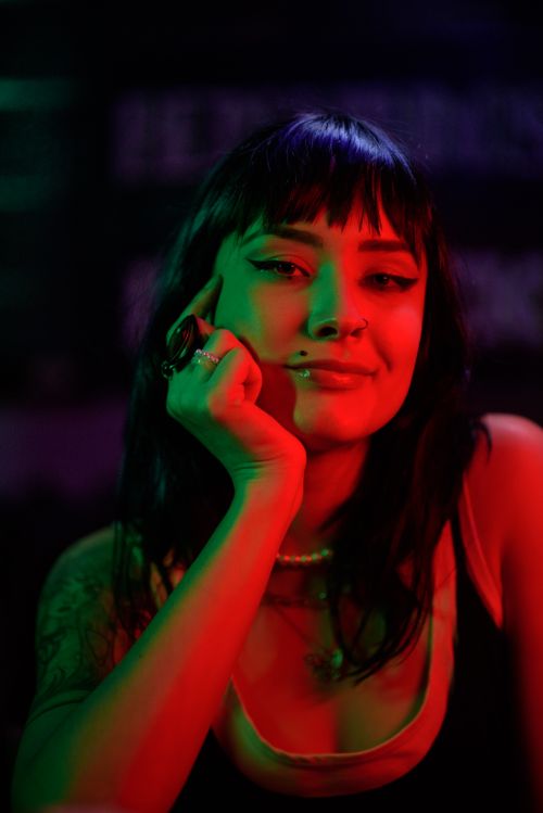 Free Captivating portrait of a young woman in neon red and green lights, creating a moody ambiance. Stock Photo