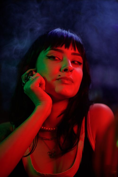 Free Artistic portrait of a woman in neon lighting, showcasing piercings and jewelry. Stock Photo
