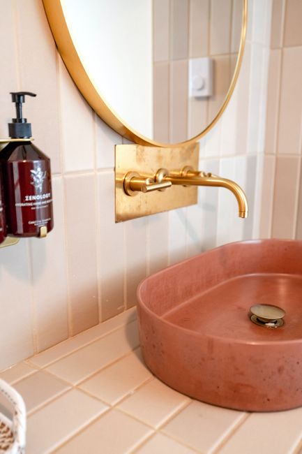 A stylish bathroom vanity featuring a modern golden tap and a chic sink, perfect for contemporary decor.