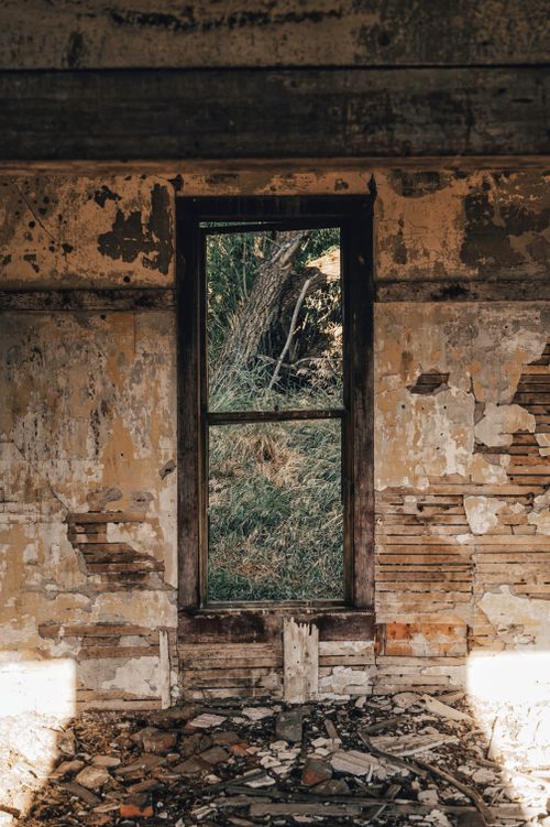 Free An atmospheric view through a broken, rustic window frame revealing nature outside. Stock Photo