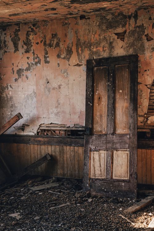 Free An abandoned interior featuring a broken wooden door and decayed walls. Stock Photo