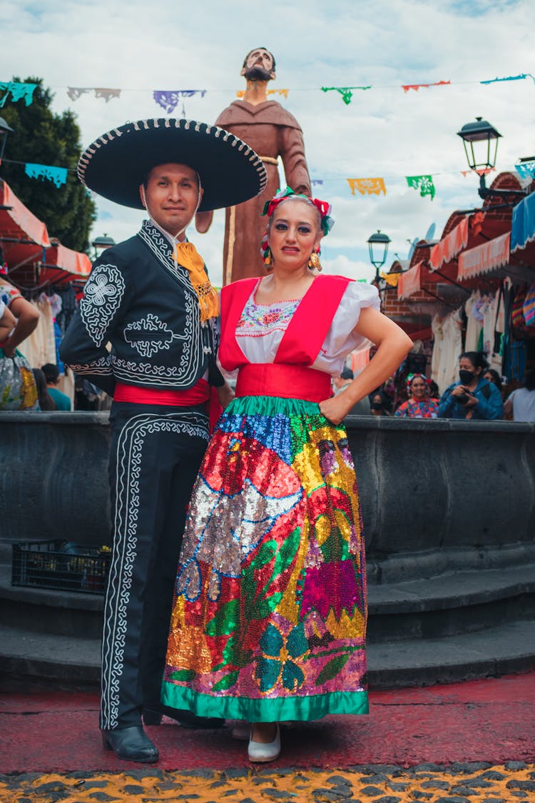 A Woman In Sequenced Dress Beside A Man In Mariachi Costume