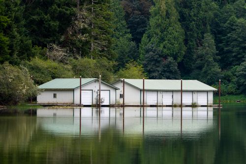 Free Peaceful floating storage sheds on a calm lake surrounded by lush green trees. Stock Photo