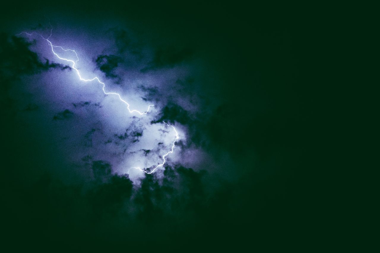 a dramatic lightning bolt illuminates a dark cloud filled night sky du