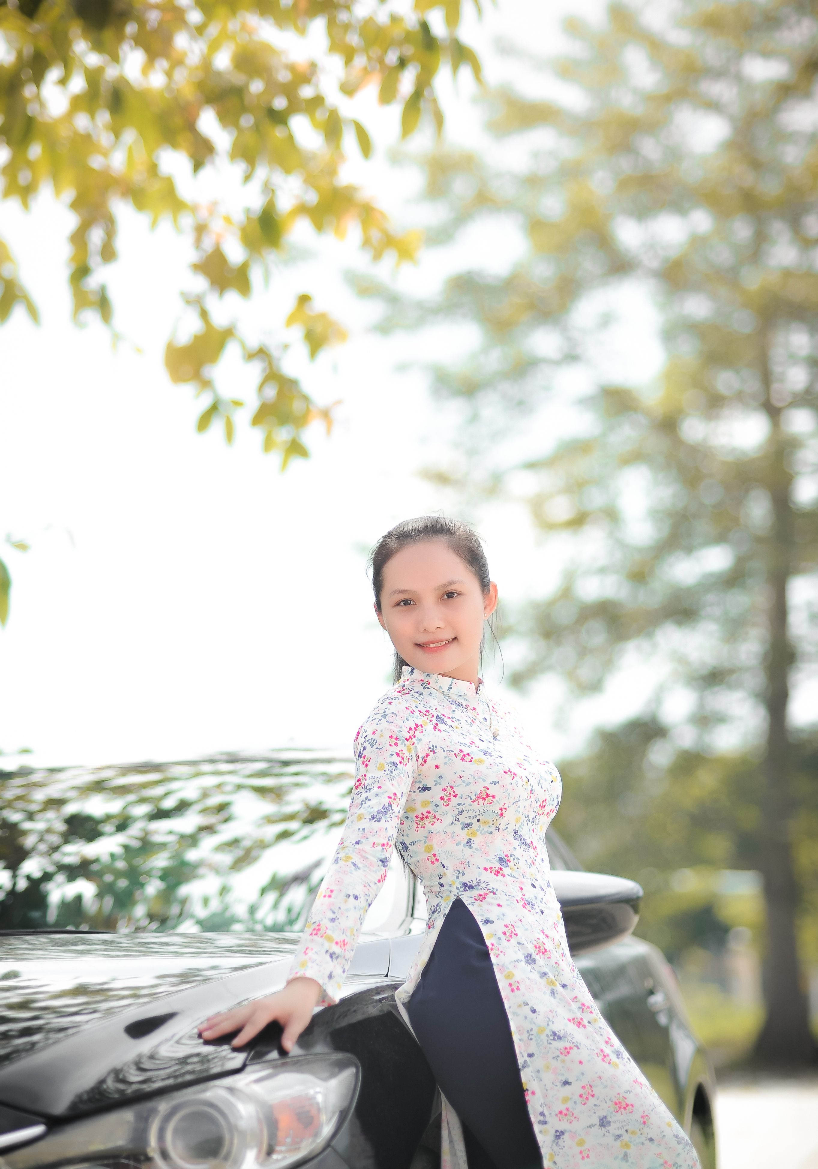 Woman in White and Pink Floral Long Sleeve Dress Leaning on Black Car ...