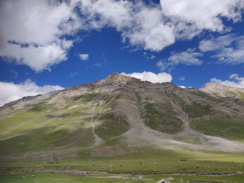 Free Stunning view of a rugged mountain under a bright blue sky with scattered clouds. Stock Photo