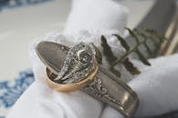 装饰性桌面上，一枚带有蕨类植物图案的金银戒指特写，尽显奢华与优雅