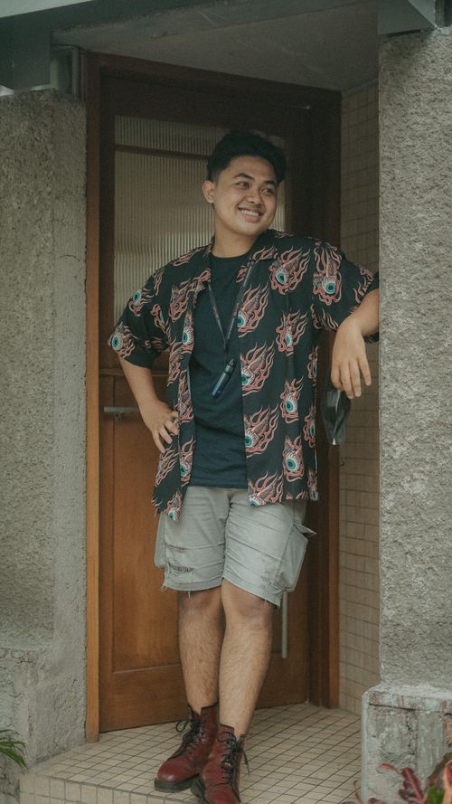 Free Young man in a stylish shirt smiling while leaning in a doorway. Stock Photo