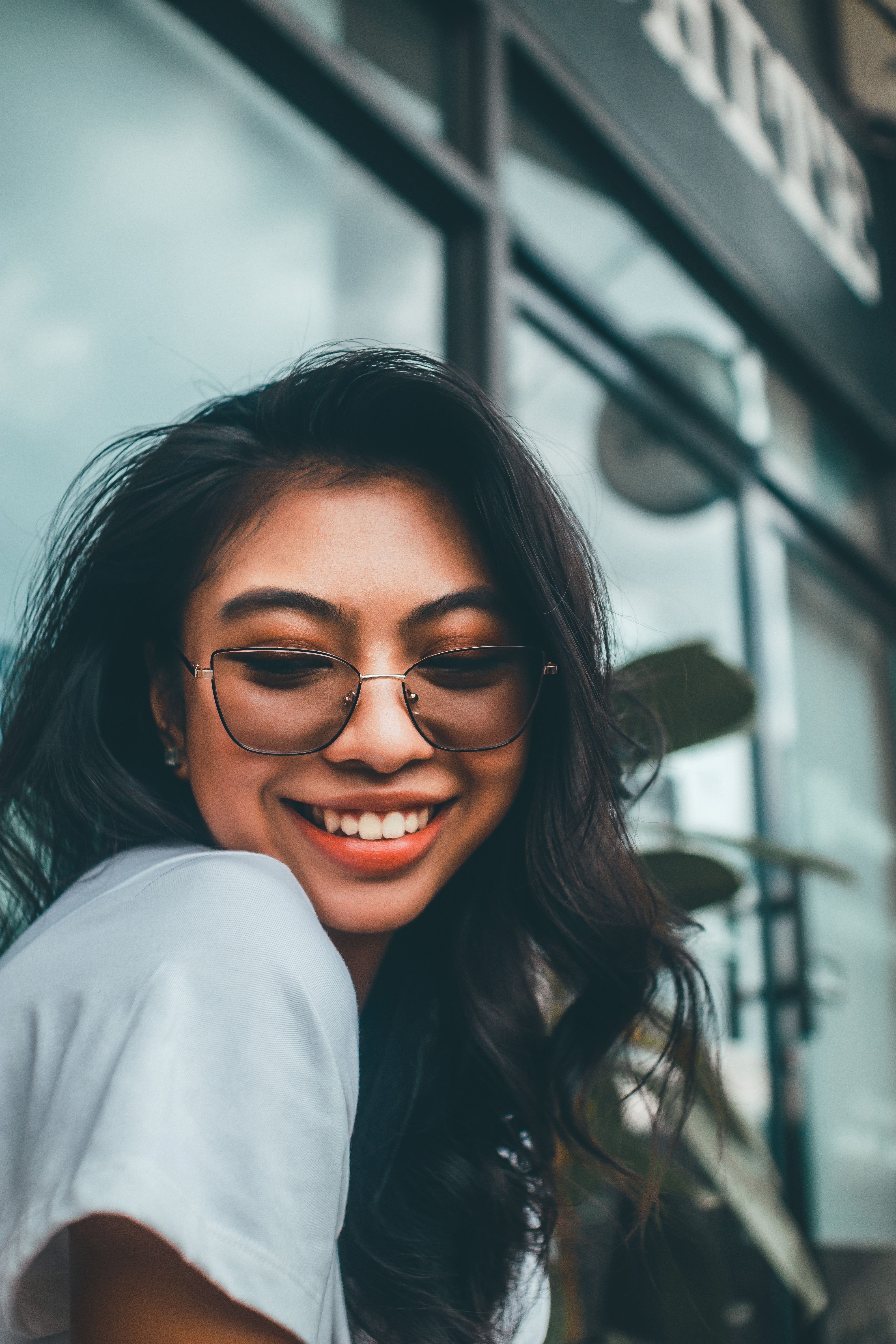 Portrait of a stylish woman smiling with sunglasses, featuring a natural expression.