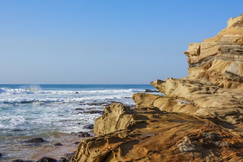 Free Stunning rock formations on Dolphin Coast, South Africa, with ocean waves crashing under a clear blue sky. Stock Photo