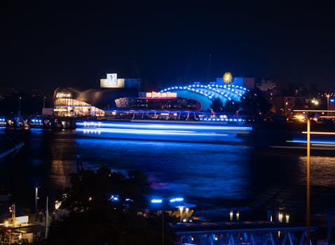 A vibrant night scene of Hamburg harbor with illuminated buildings and reflections on water.